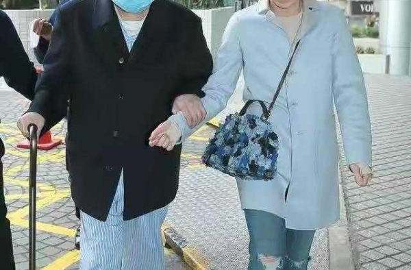 “阔太”甘比真低调，穿淡蓝色长外套配牛仔裤，看不出豪门气质